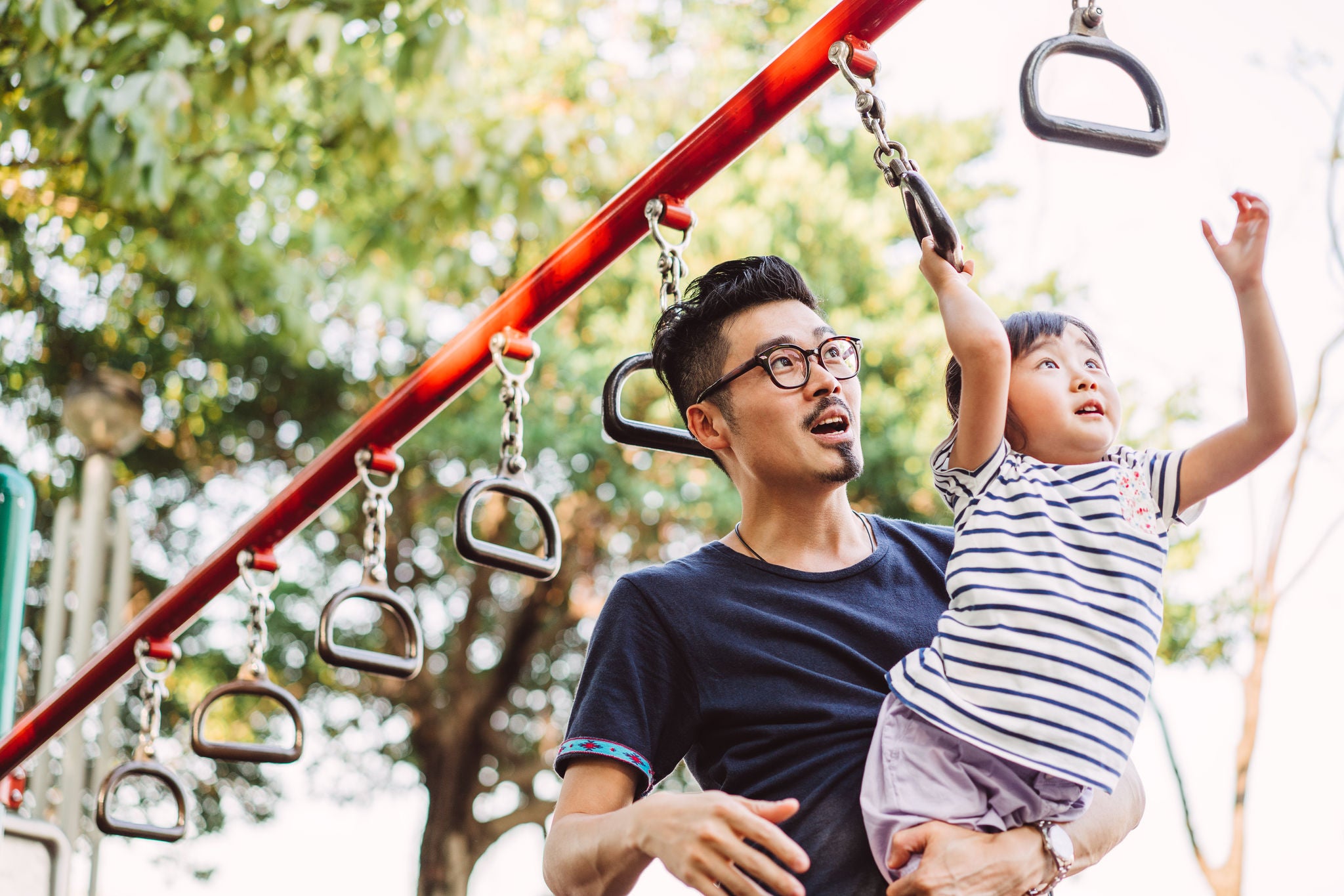 Young dad and little daughter doing exercise together in the sports ground joyfully