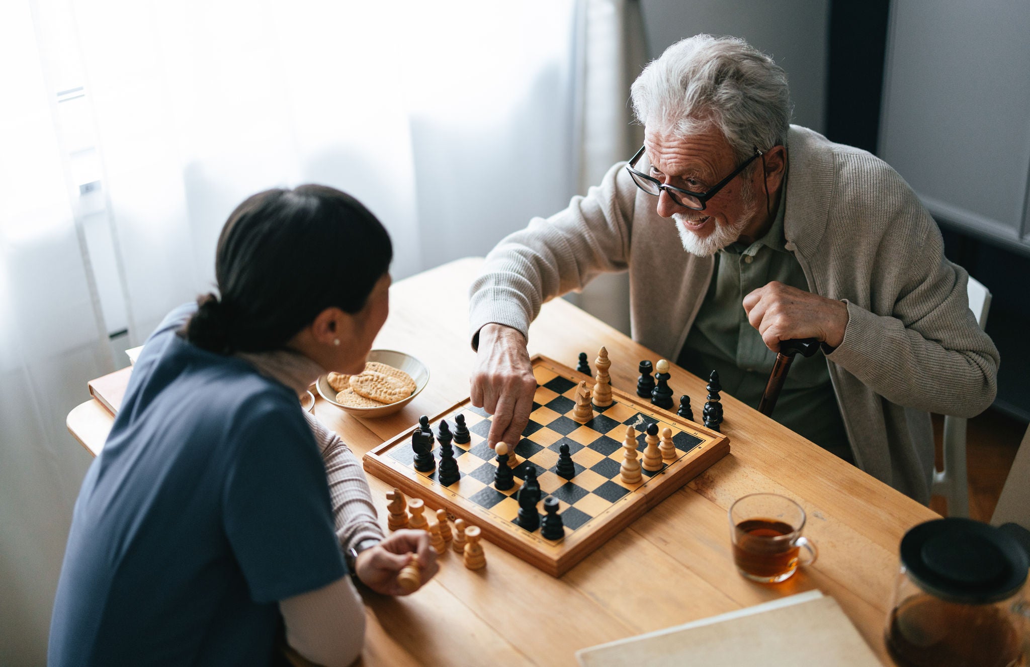 High angle view of unrecognizable Japanese female caregiver having fun with a smiling elderly patient in the nursing home.