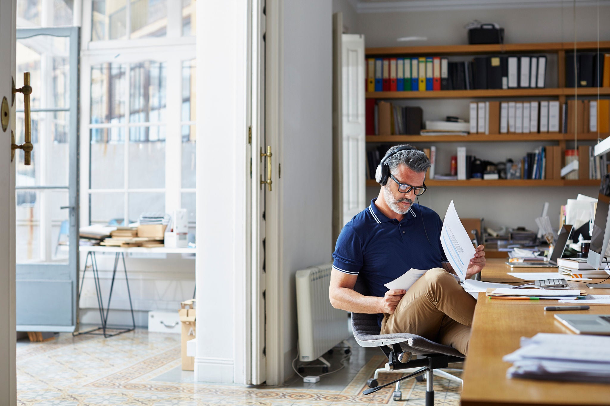 Mature businessman examining documents at desk in office