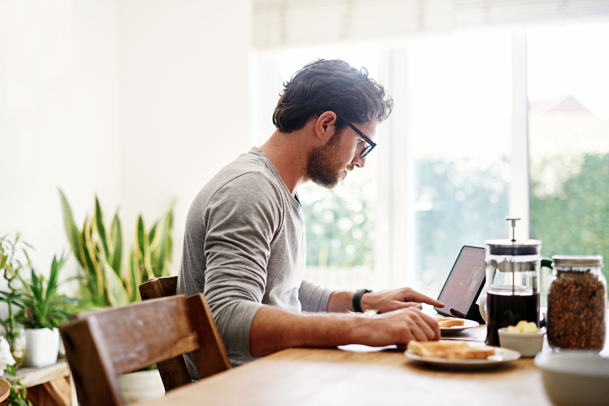 Shot of a young man using a digital tablet while having breakfast at home