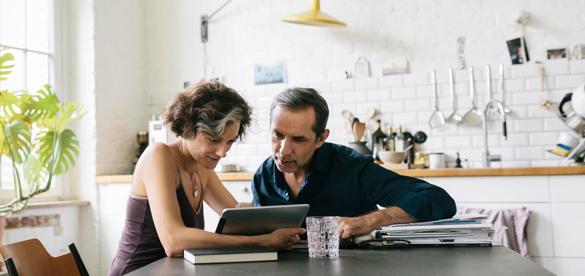Mature couple sitting at the breakfast table using a computer tablet.