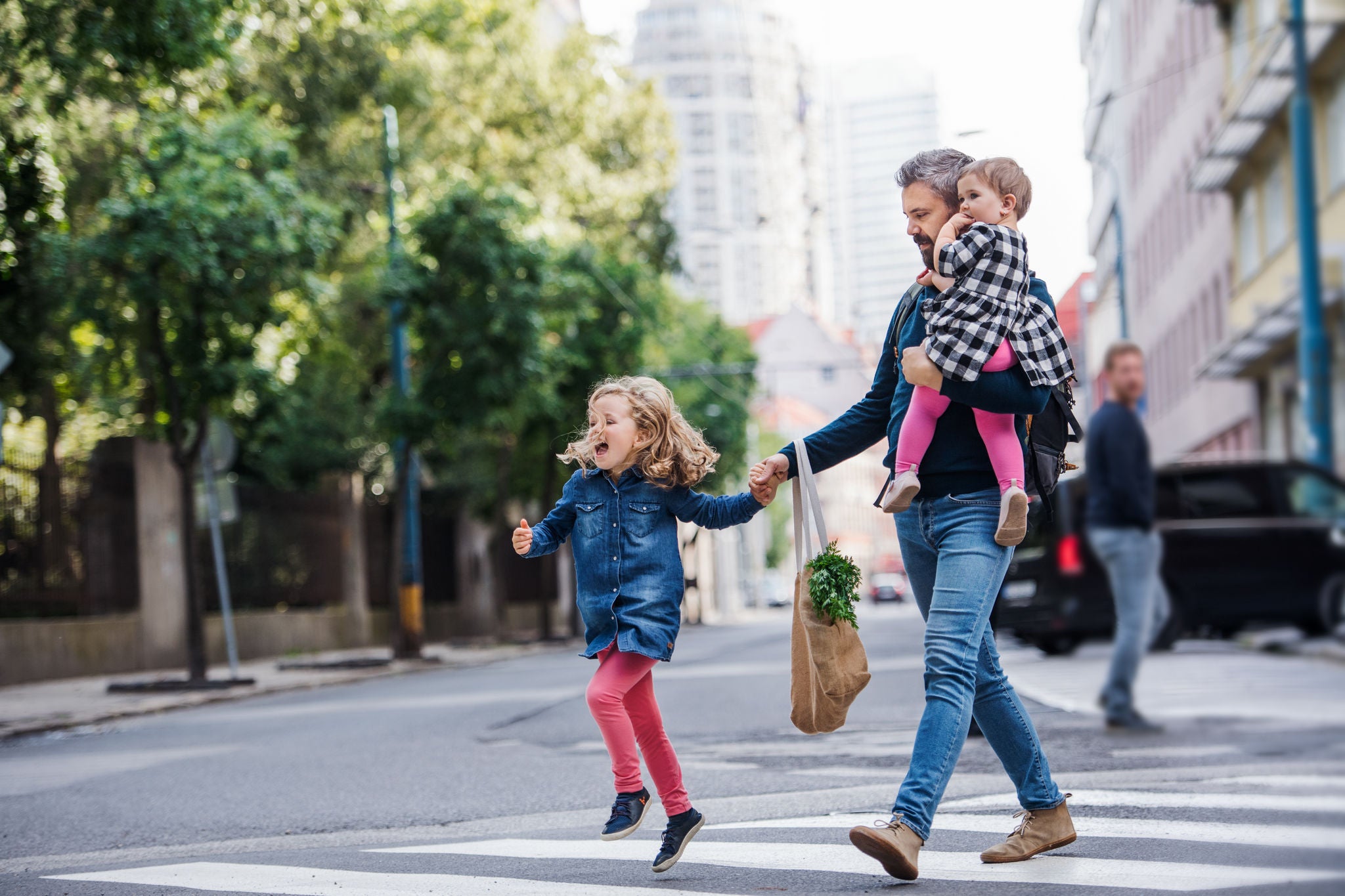 Man with daughters walking in town.