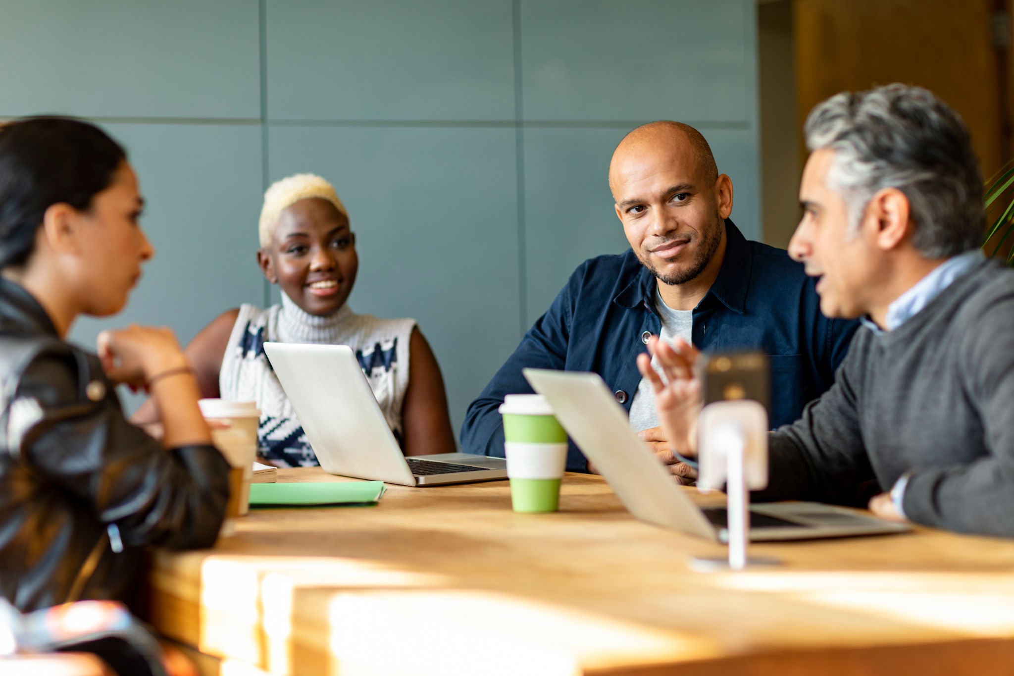 Four business people in business meeting with colleagues discussing project, teamwork, togetherness, connection