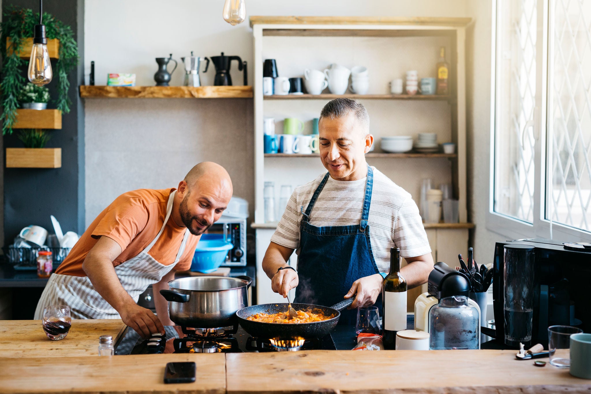 Mid adult gay couple talking and having fun while cooking in a kitchen