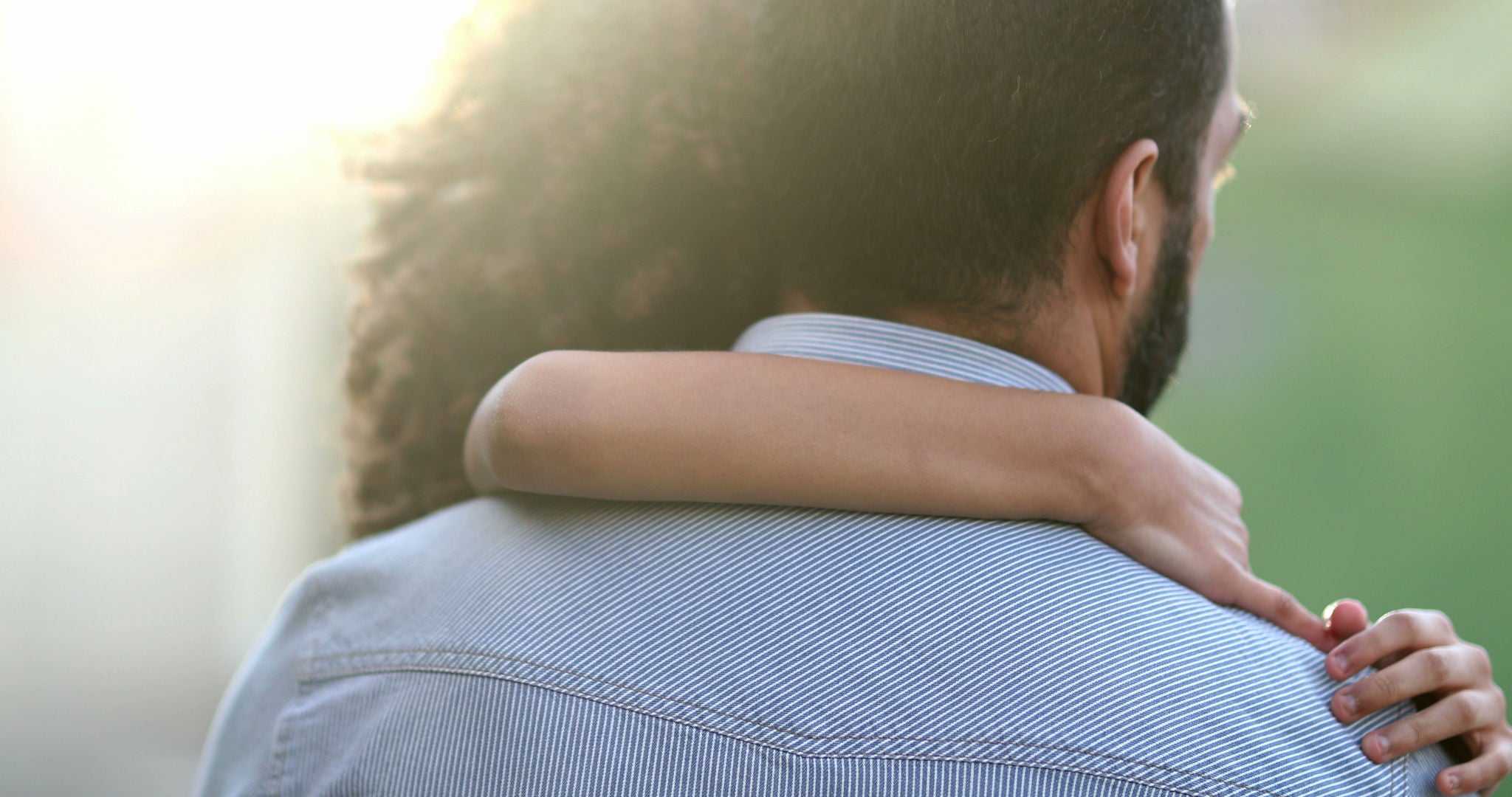 Daughter hugging father outside. Mixed race ethnicity little girl hugs dad