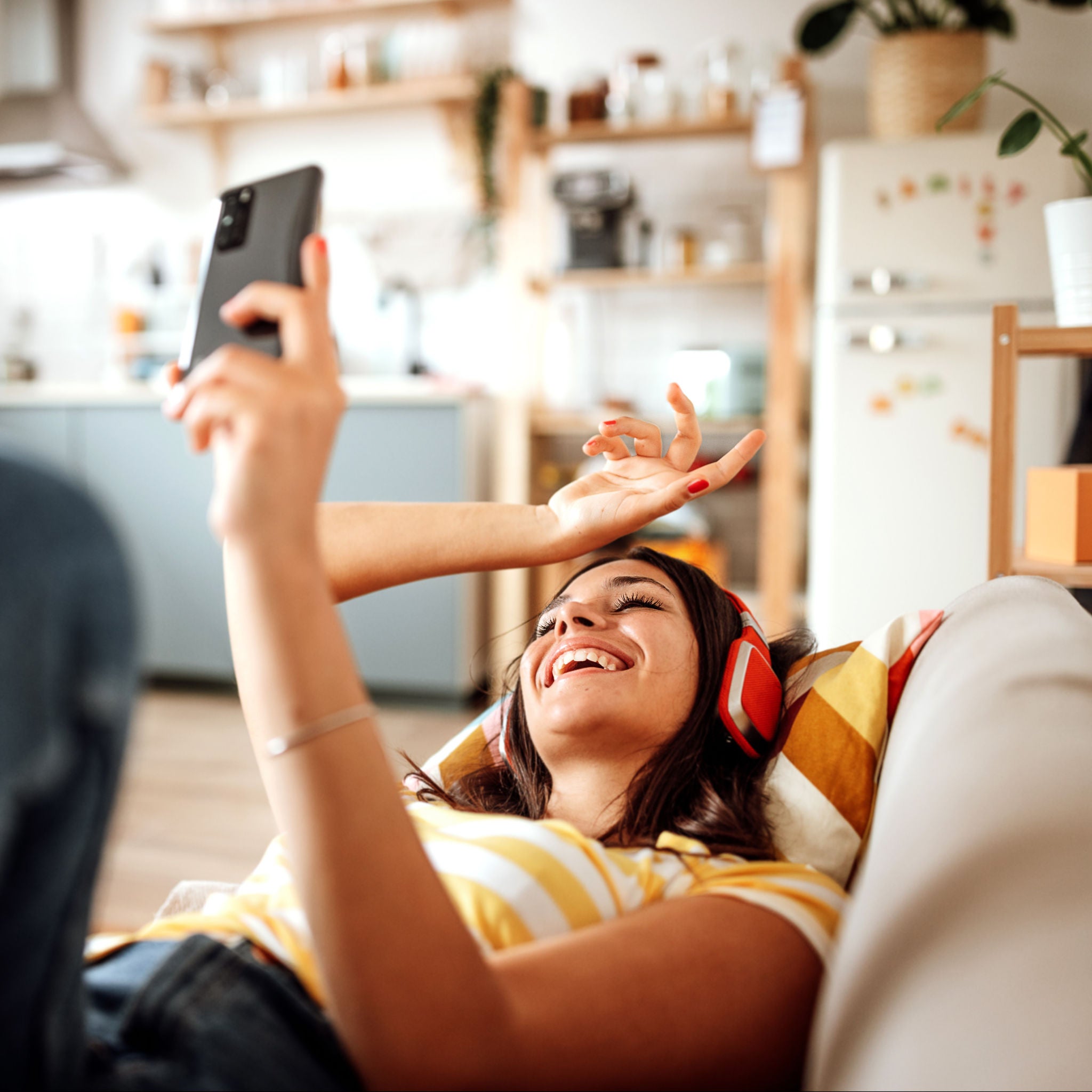 Beautiful young woman listening to music on headphones at her cozy apartment