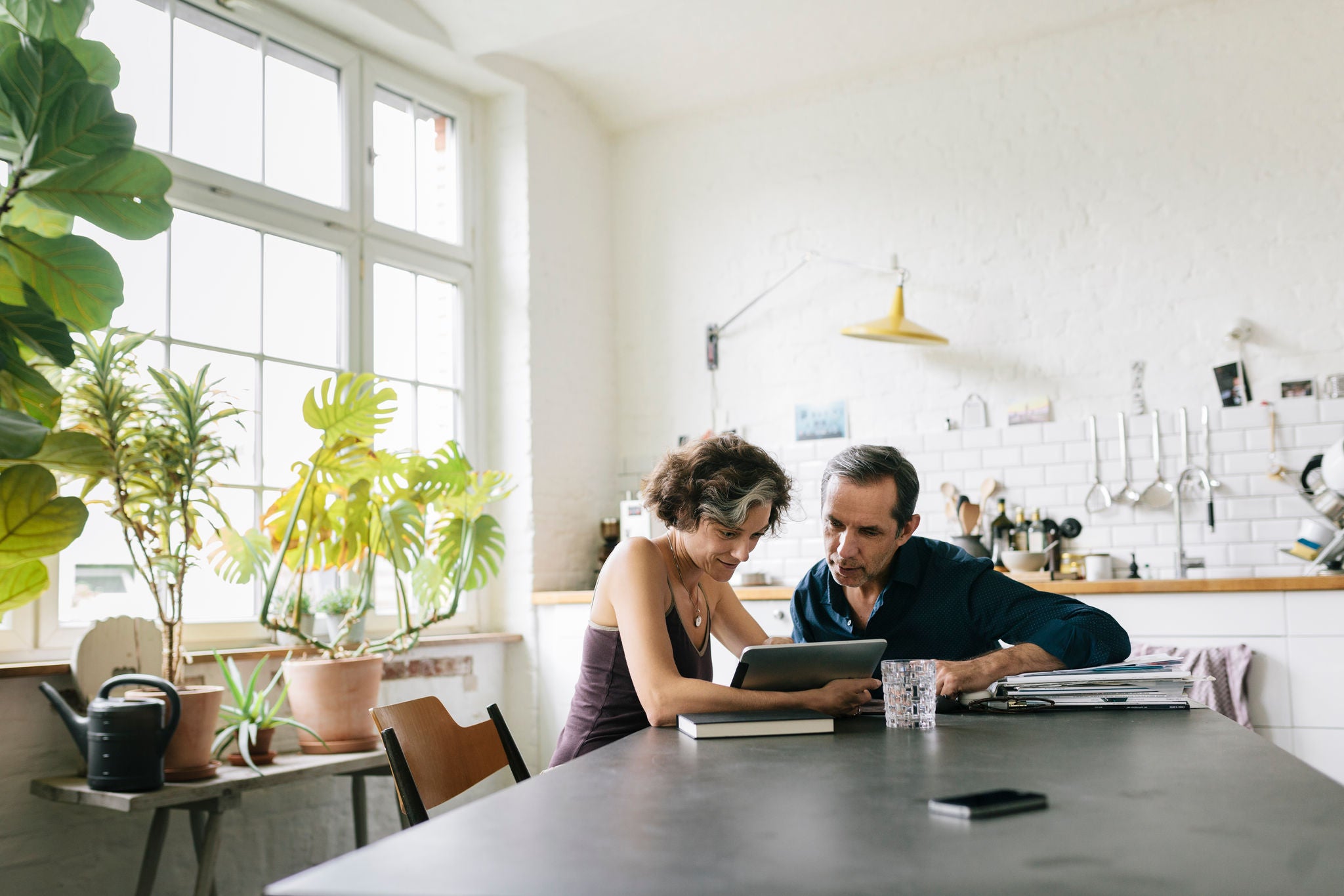 Mature couple sitting at the breakfast table using a computer tablet.