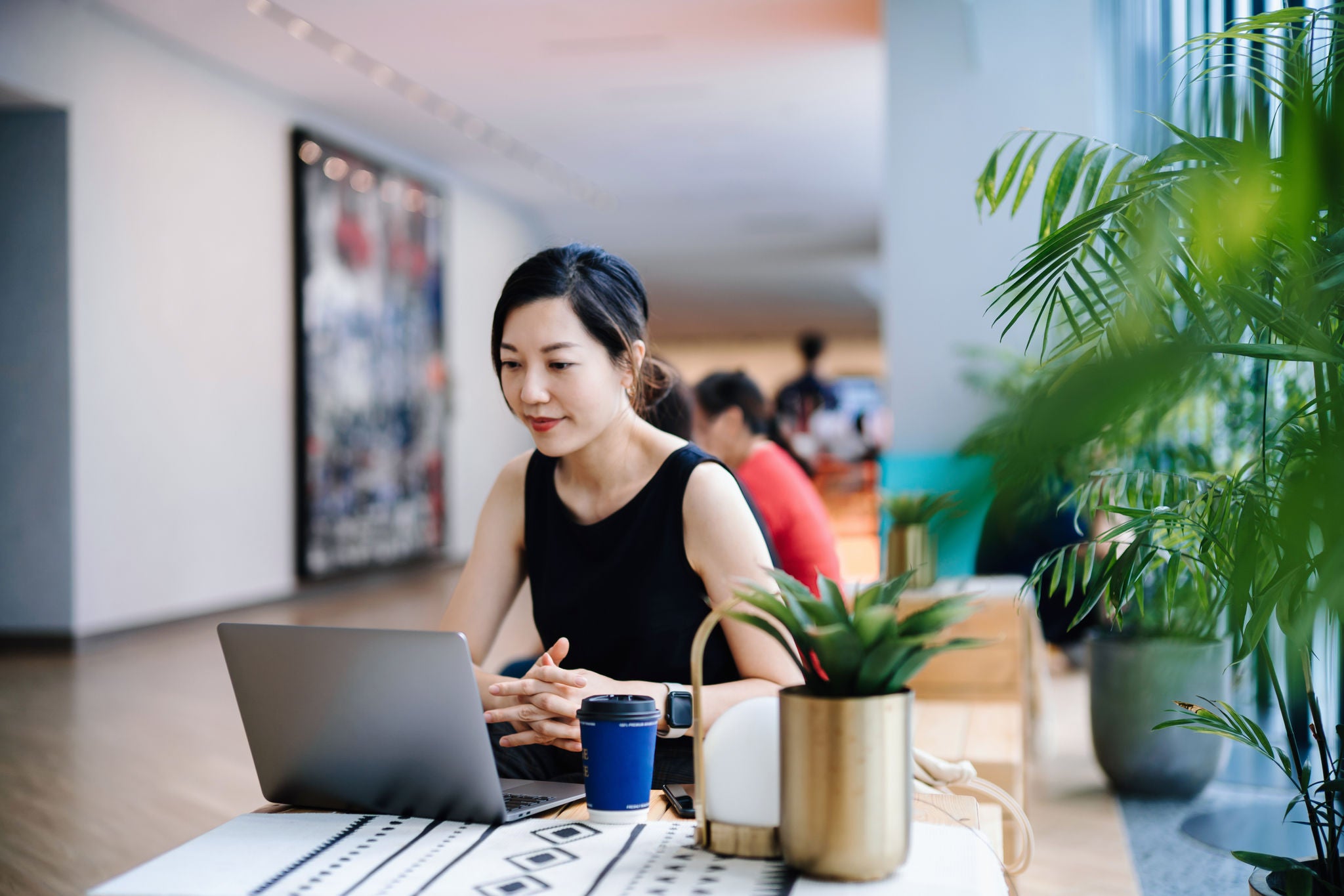 Young Asian businesswoman working in a modern office space while talking in front of the camera having video conference with her business partners on laptop. Virtual business meeting. Making business connections with technology